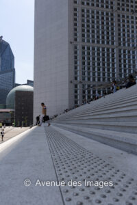 Walking with a briefcase down the steps of the Grande Arche in Paris La Défense