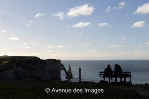 Couple in silhouette overlooking the aiguille of Etretat and the Aval Cliff